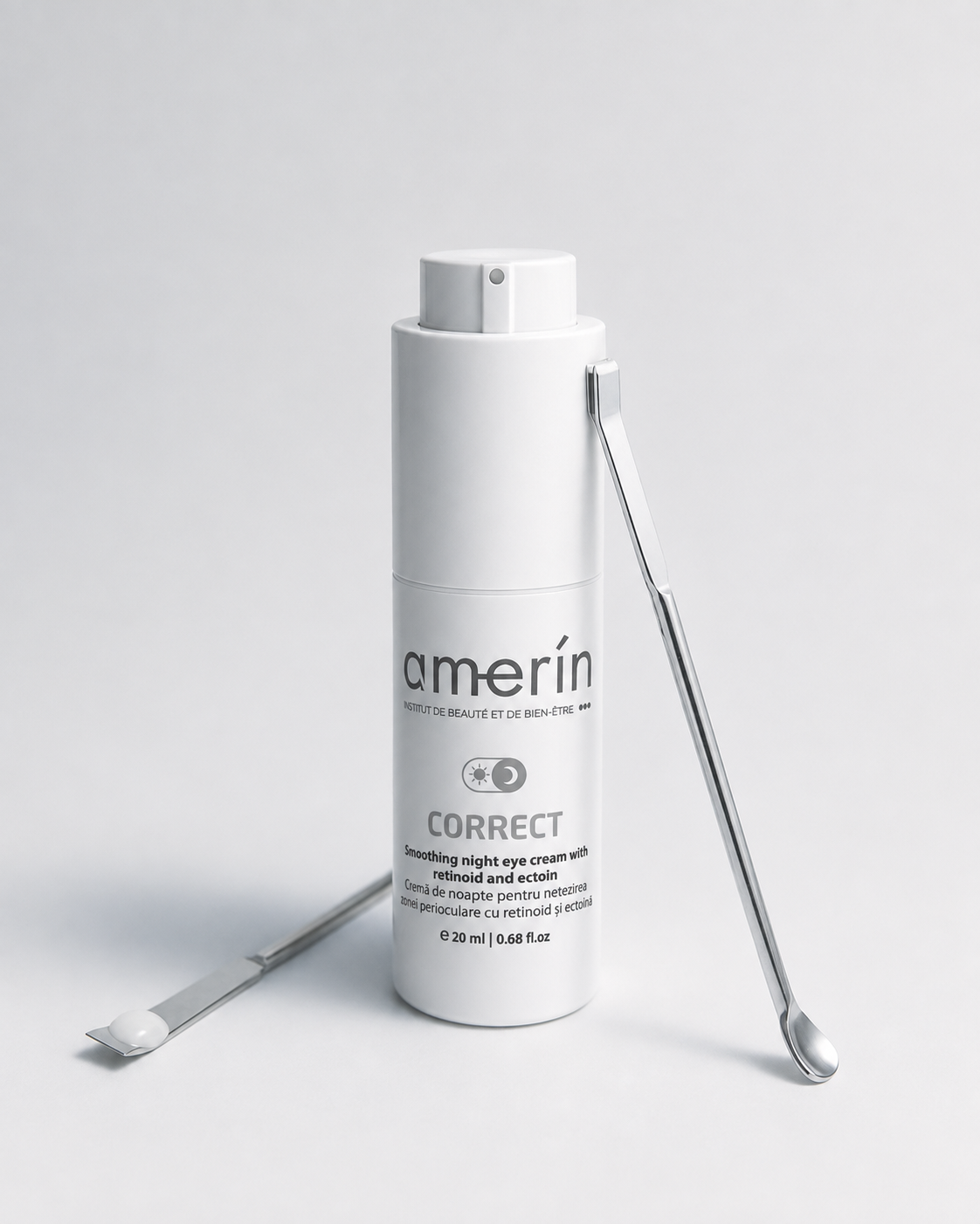 A white cylindrical cosmetic bottle labeled amerín CORRECT smoothing night eye cream, shown on a light gray studio background with two silver metal spatula tools placed beside it.