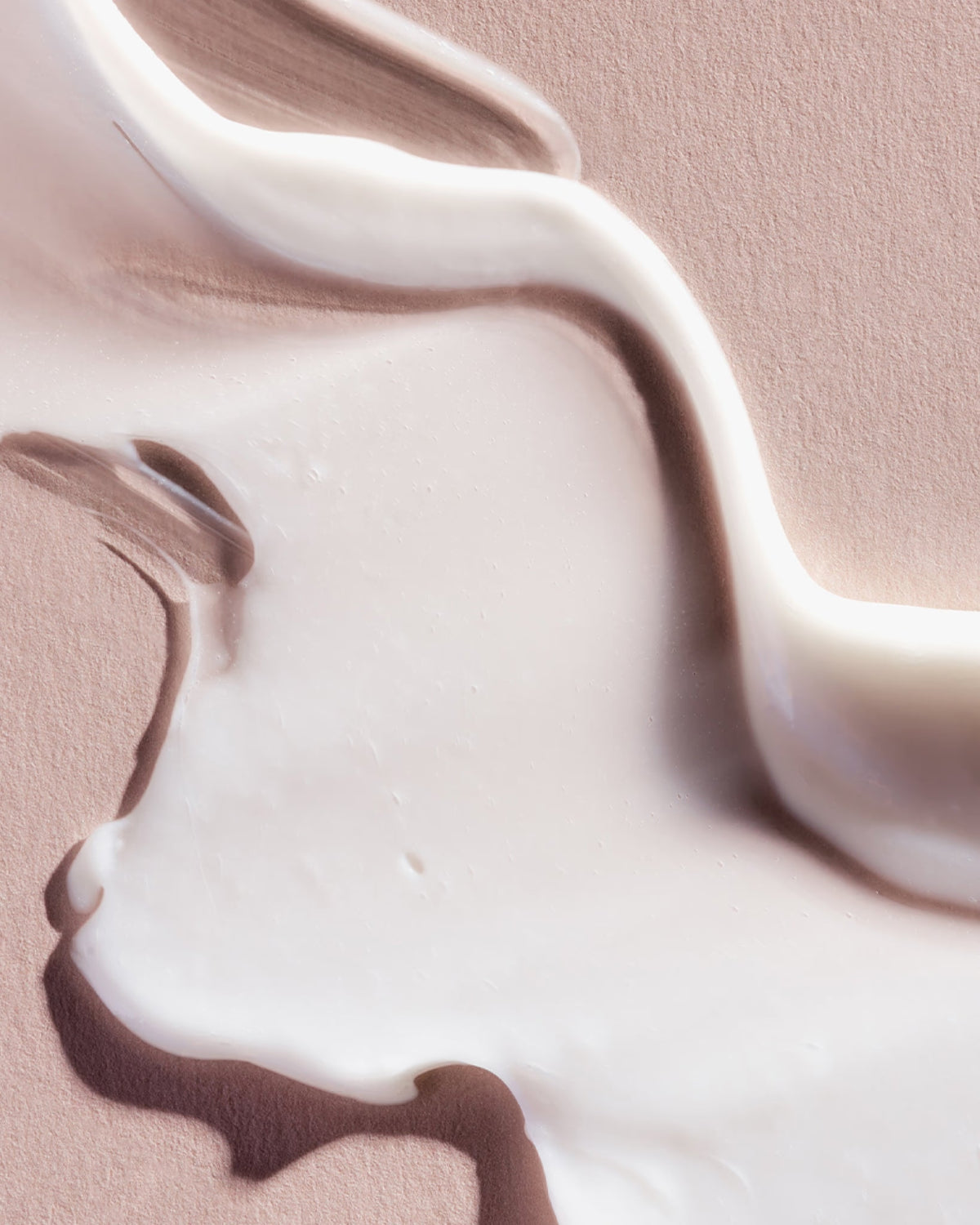 Primo piano di crema o vernice bianca su sfondo rosa